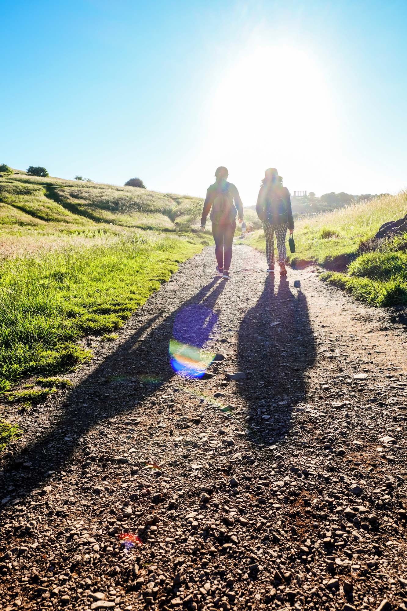 Rear view of people walking on a trail with long shadows